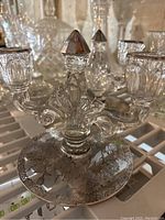 Close-up photo showing ornate crystal butter dish with floral etchings and a crystal candle holder with metallic candle sockets.