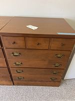 Front view of the dresser showing three small top drawers with wooden knobs and three larger bottom drawers with brass handles.