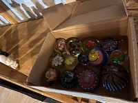 All twelve assorted glass paperweights displayed in cardboard box