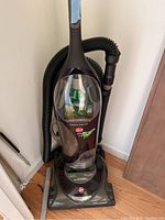 Full view of the Hoover upright vacuum cleaner showing the base, dustbin, hose, and handle with taped grip.