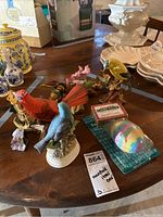 View of assorted bird figurines, a boxed package, and a colorful holiday item on a wooden table
