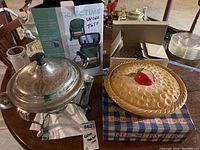 Photo of metal chafing dish, apple motif ceramic pie plate in box, and boxed wine tote