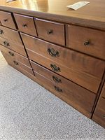 Front angle view showing six drawers with different handles on a wooden dresser.