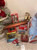 Full view of the lot showing various Christmas items including gift boxes, wrapping paper, ornaments, and decorative bells arranged on carpet.