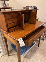 Full view of vintage wooden desk with top drawers open, showing small side drawers, central cabinet with doors open, and top surface with scratches.