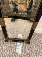 Bottom portion of the mirror showing the reflection of items on floor and some of the frame detailing.