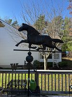 Full view of the horse atop the weathervane showing the mounted design on a pole outdoors.