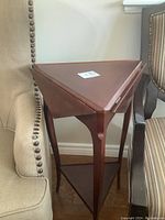 Full view of triangular accent table positioned between chairs, showing overall shape and finish