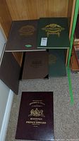 Four cloth-bound atlases on a shelf with burgundy, brown, and green covers