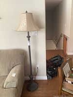 Full view of floor lamp showing beige cloth shade and metal stand next to couch