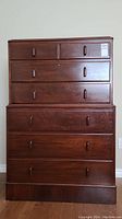 Front view of solid wood highboy dresser showing seven drawers with wooden pulls and locking drawer.