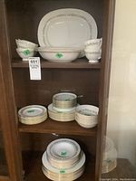 Full cabinet with complete dinnerware displayed including plates, bowls, cups, saucers, and serving platters.