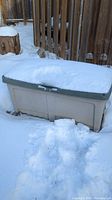 Resin patio storage box covered in snow showing overall shape and outdoor placement