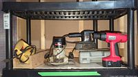 Shelf with four power tools: yellow Sabre jig saw, black Sears router, Black & Decker corded hand sander, and red-black Bolton 18V cordless drill.