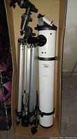 Side view of the full telescope and tripod set inside a cardboard box showing 33.5 inch optical tube and tripod.