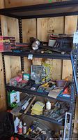 Photo showing shelves with various tools and hardware including boxes, chainsaw, hammer, mallet, electrical items and accessories.