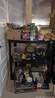 General overview of assorted hardware and tools on black shelving unit with boxes and tool containers.