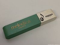 Closed original box for Hohner melodica soprano in teal and white with branding.