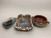 All three pottery items displayed together on white background: rectangular serving pan, flower frog tray, and lidded pottery pot.