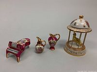 Full set of four Limoges bone china miniatures including birdcage, piano, and two small pitchers.