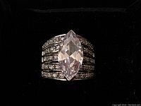 Close-up top view of the silver ring highlighting the marquise-cut clear crystal center stone and rows of smaller crystals on the band.