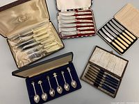 Overview of various antique and vintage cutlery sets and collector spoons in their original cases, showing the assortment included in the lot.