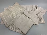 Stack of beige linen napkins and placemats folded, showing fabric texture and edges