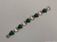 Full view of the linked bracelet showing the alternating silver and green stone triangular links.