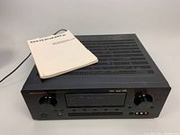 Front-top angled view of the Marantz SR7200 AV Surround Receiver with manual placed on top.