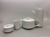 Full set showing coffee pot, teapot, sugar bowl, and creamer arranged in a row on gray background