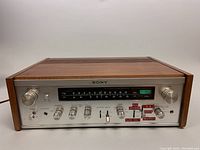 Front wide view of Sony STR-7045 FM Stereo/FM-AM Receiver showing wood side panels and full front panel with control knobs and frequency display.