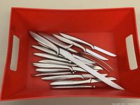 All 14 utensils displayed in red tray showing the carving knife, fork, and 12 steak knives.