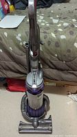 Front full view of Dyson DC25 upright vacuum cleaner on carpet showing overall condition and design.