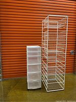 ELFA metal shelving unit with 7 wire baskets on the right and Gracious Living plastic storage organizer with 5 drawers on wheels on the left, against a storage facility background