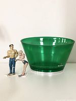 Large green acrylic Heineken ice bucket with two vintage Bottoms Up Ganz beer/soda can holder figurines displayed together