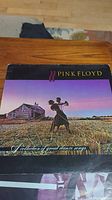 Front cover of Pink Floyd A Collection of Great Dance Songs showing two people dancing in a field during sunset with a house in the background.
