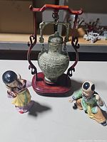 Overview of all three items showing two figurines and the decorative bell with stand