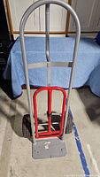 Full front view of red and grey metal hand truck dolly showing the handle and base platform.