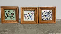 Three framed bird tile art pieces on the floor, showing all designs