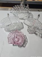 Top view of the four crystal baskets showing their shapes and patterns, including pink basket and various clear glass patterns.