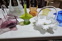 Overview shot showing all 7 vintage glass baskets in an assortment of colors and styles on a white surface.