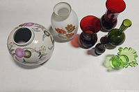 Seven diverse vintage vases including ceramic and glass materials arranged in a group on a white surface.