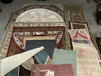 View of multiple area rugs laid out on the floor, showing rectangular, octagonal and runner styles with varying colors and patterns.