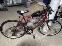 Side view of red Fuji ATB MX100 mountain bike with black gas motor and tank, showing frame, tires, pedals, and gear system