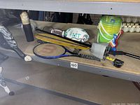 Metal detector (Bounty Hunter Discovery 3300) on shelf with skateboard, rackets, footballs, and sand pails.