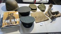 Overview photo displaying all hats, helmet, body yoke piece, and books on a table with good lighting