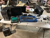 Wide shot of electronics on table showing multiple monitors, computer towers, networking routers, IP cameras, and accessories.