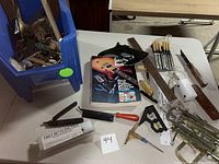 Full view of the lot showing the guitar repair guide book, various hand tools including files, knives, hammer, and ruler, along with a box containing additional smaller components and tools.