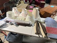 Photo of a table displaying fabric lampshades, curtain rods, and various hardware