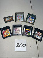Photo showing seven different Nintendo GameBoy game cartridges laid out with labels visible including Super Mario Deluxe, Tetris, Bust A Move, Super Bust A Move, Gex 3, Shanghai Pocket and Ghosts n Goblins.